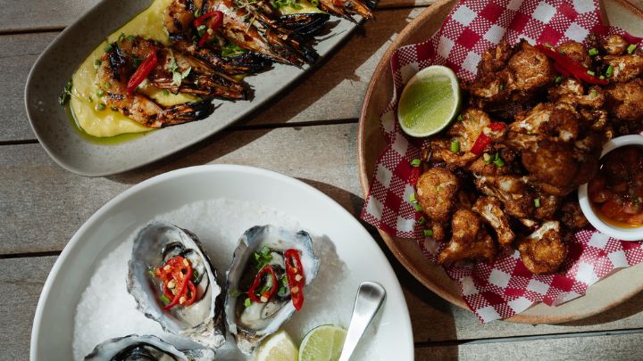 Three dishes of oysters, prawns, and chicken on a table