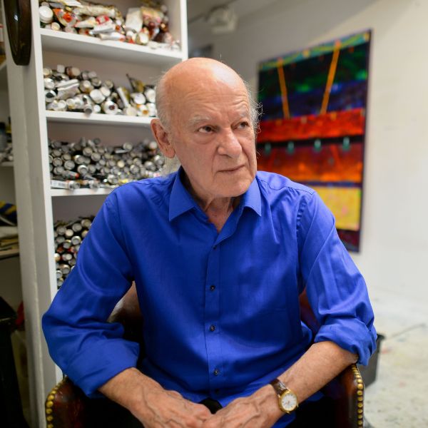 A man in a dark blue shirt sits in an art studio