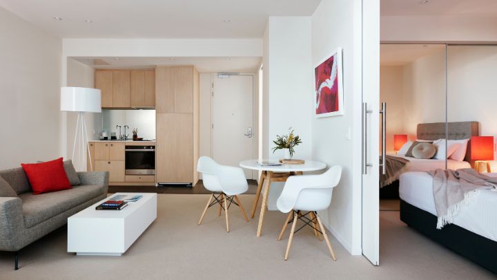 Hotel apartment with a grey sofa, white dining setting and red artwork