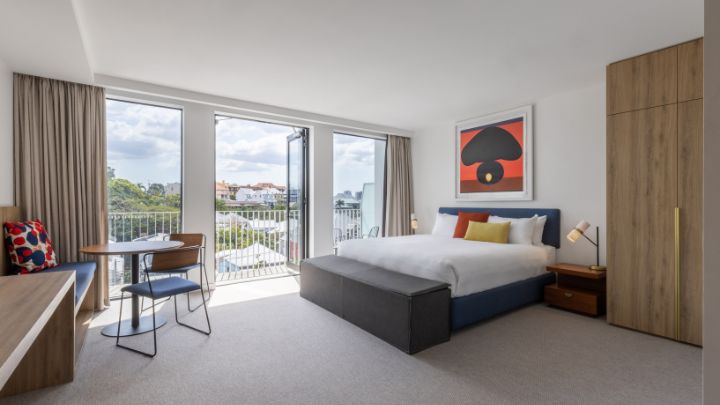 A hotel bedroom with a king sized bed and large windows